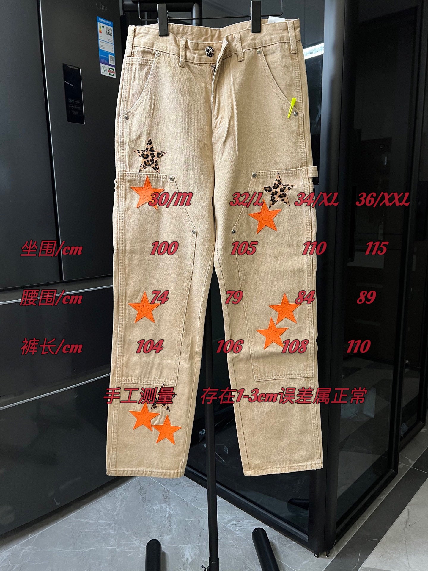 Light khaki pants with orange star patches and printed size markings