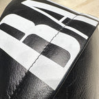 Balenciaga men’s black leather backpack close-up of white logo lettering on surface