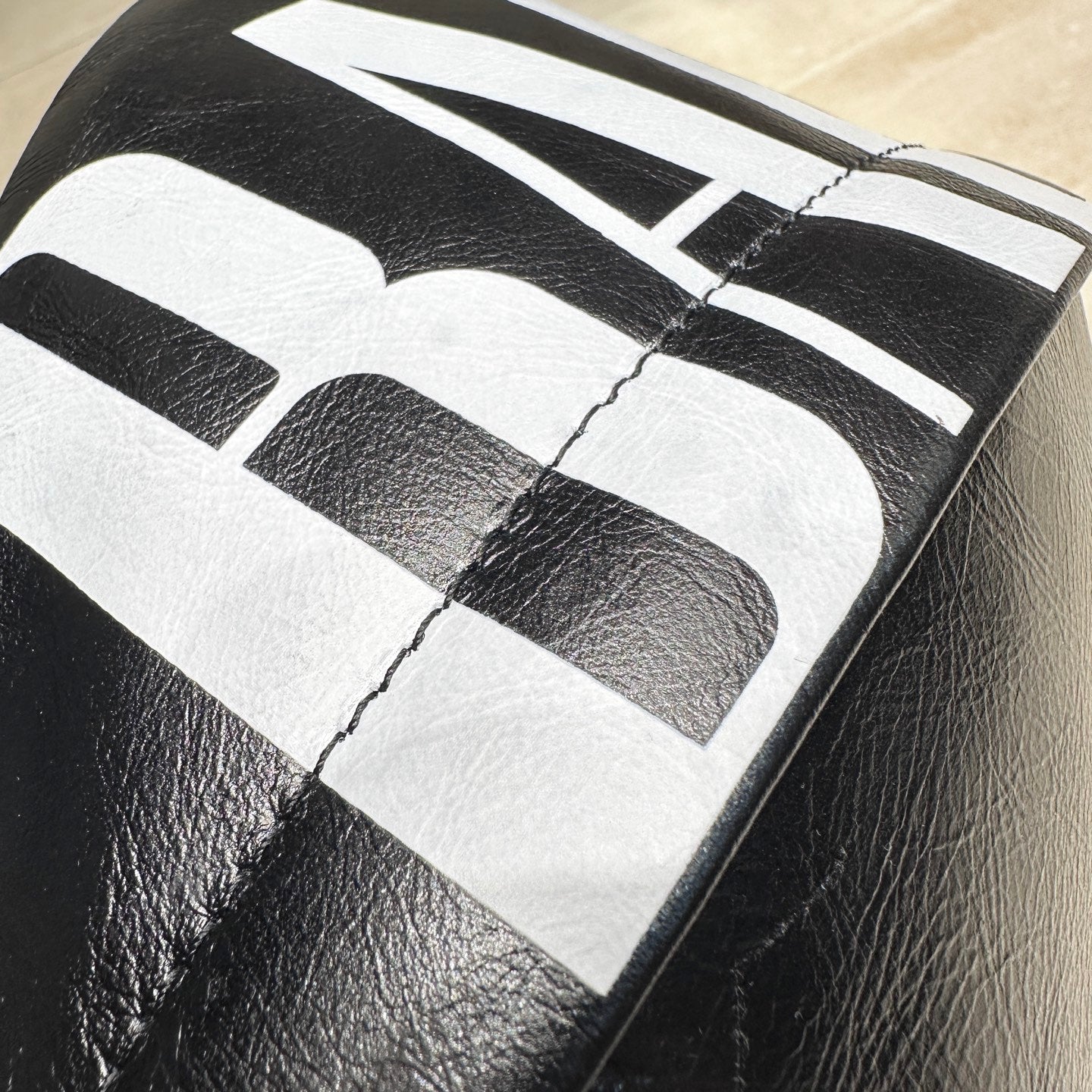 Balenciaga bag close-up of large white logo print on black leather panel.