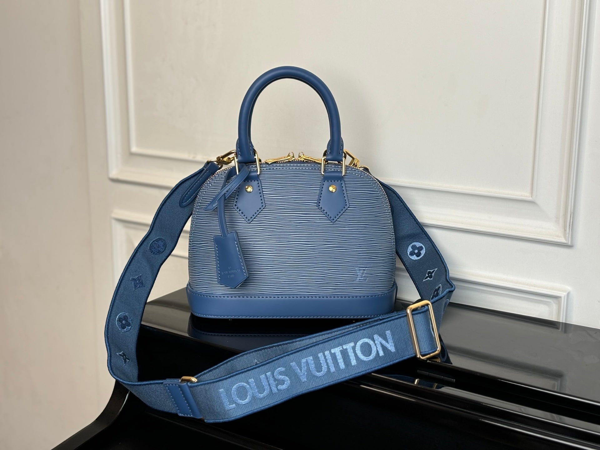 Blue Louis Vuitton handbag with two top handles, textured exterior, gold hardware.