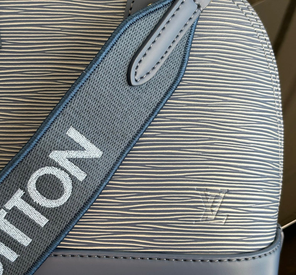 Blue Louis Vuitton strap close-up with bold lettering on textured material.