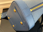 Blue Louis Vuitton handbag side close-up with stitched panel and gold snap buttons.