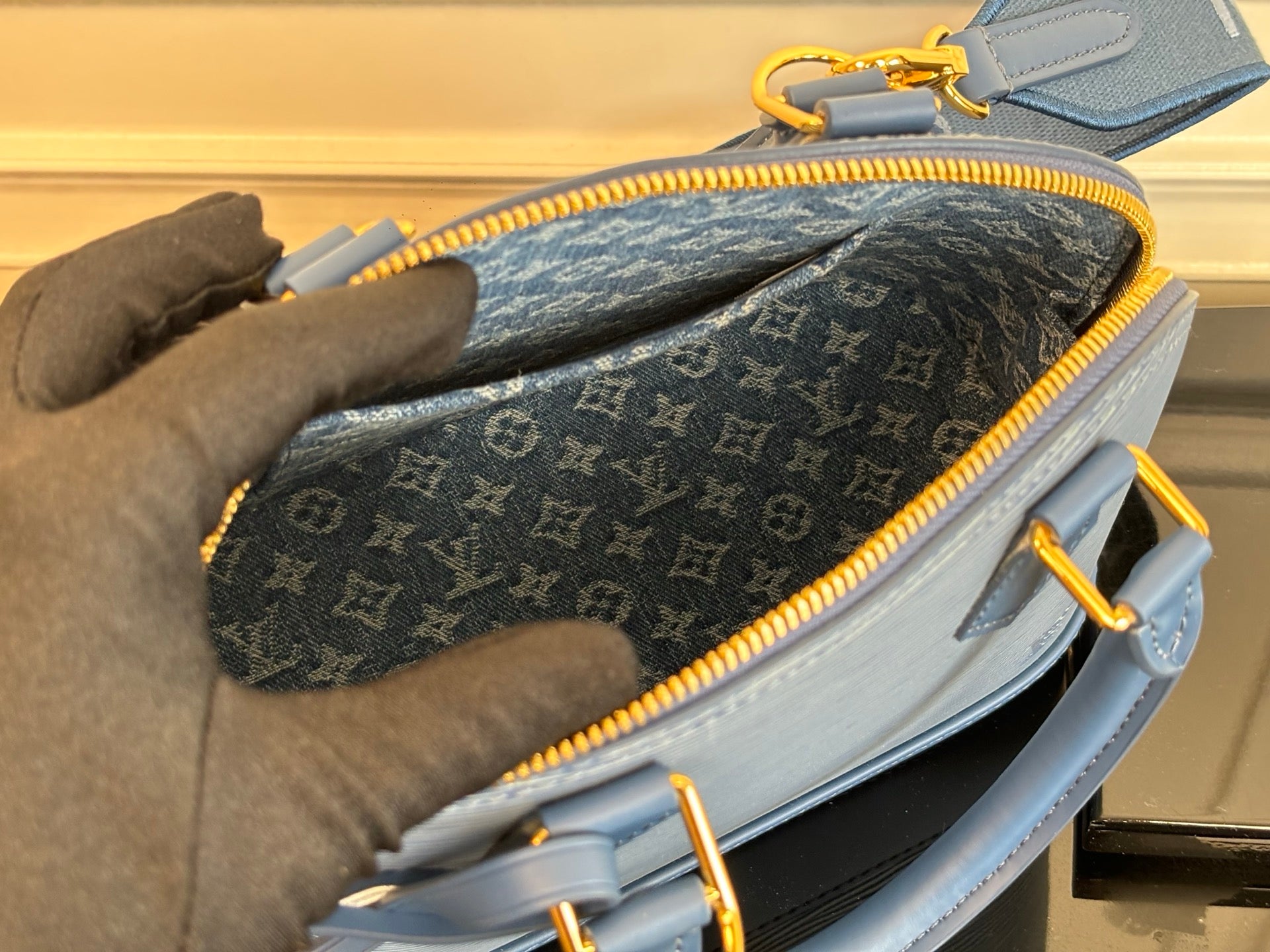 Louis Vuitton handbag open view with dark monogram interior and yellow zipper.