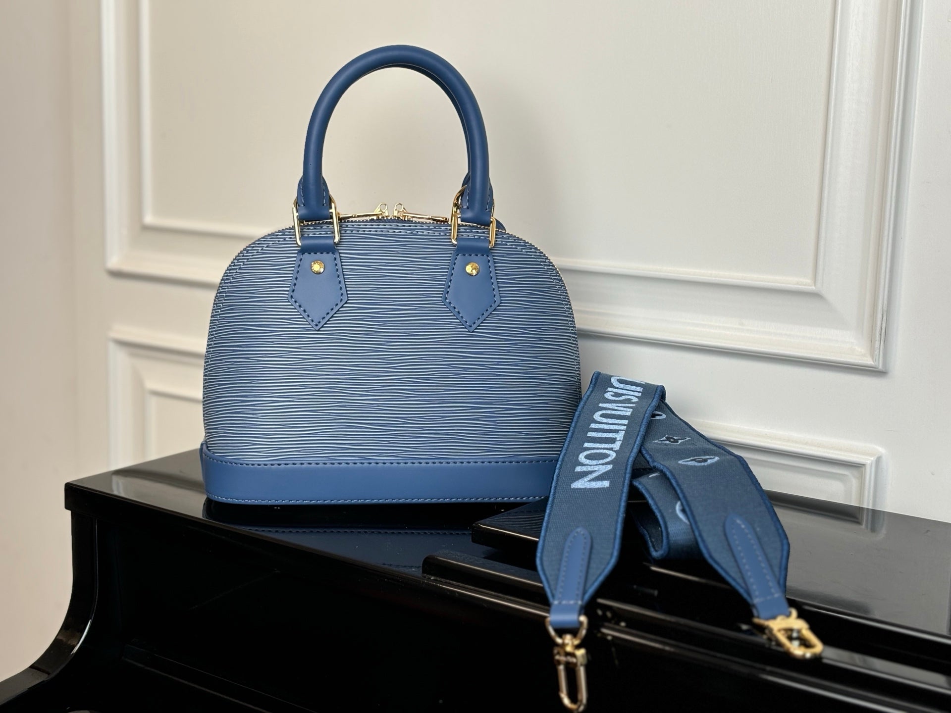 Blue Louis Vuitton handbag display view with shoulder strap and top handles.