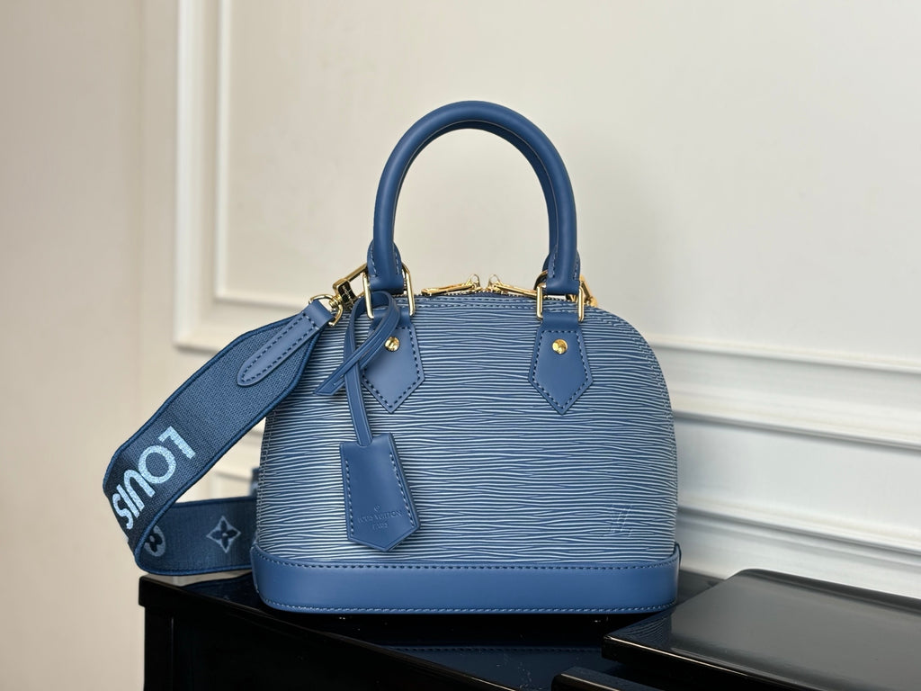 Blue Louis Vuitton handbag front view with two top handles and leather side tabs.