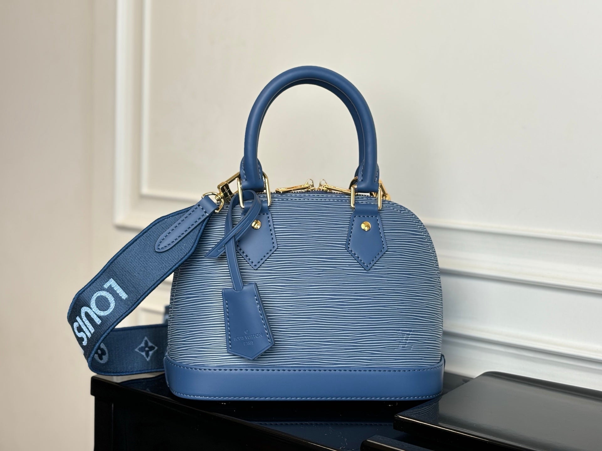 Blue Louis Vuitton handbag front view with two top handles and leather side tabs.