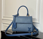 Blue textured leather handbag with top handle, front flap, and gold-tone hardware.