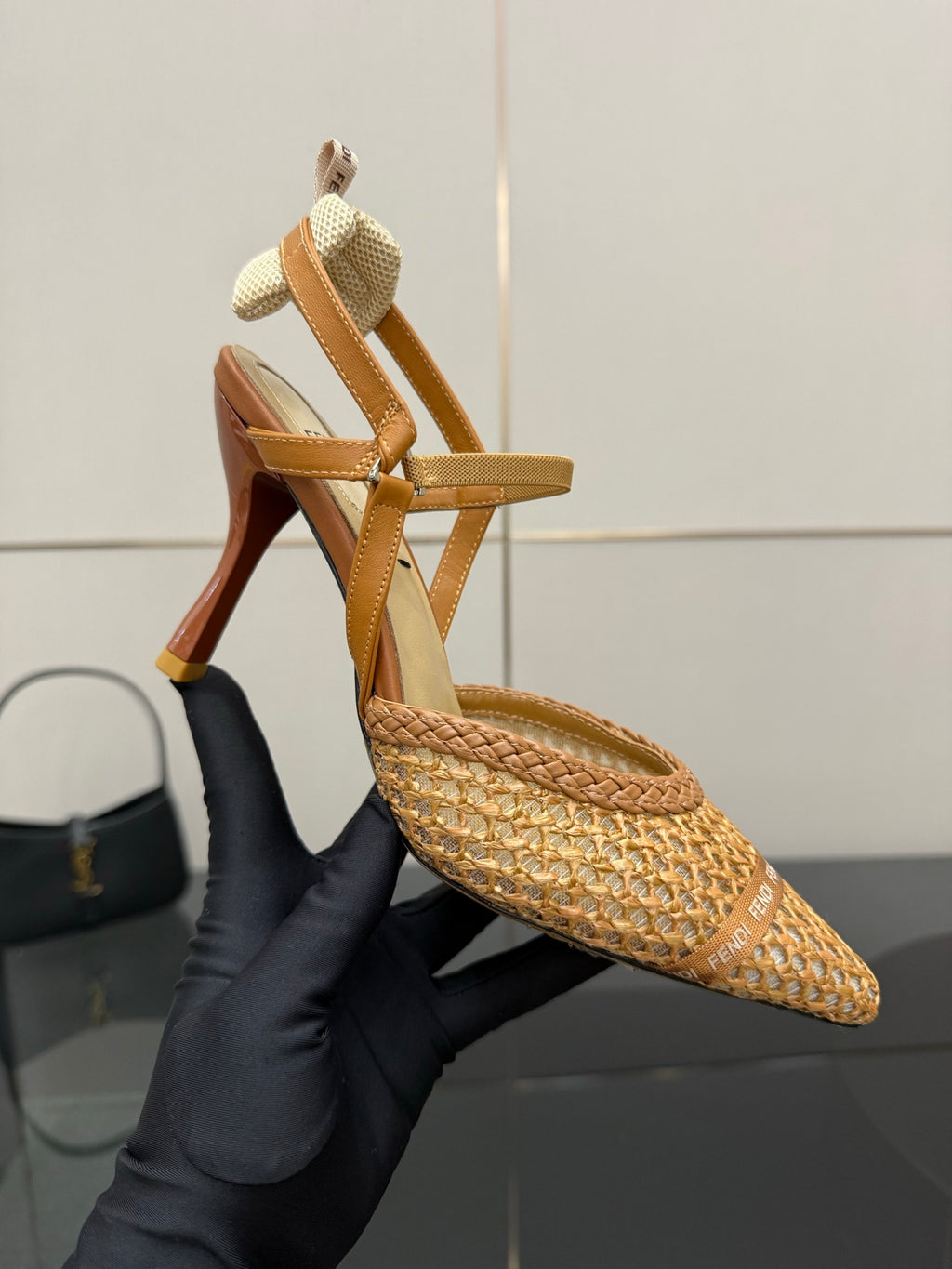 Tan woven heeled sandal with T-strap and pointed toe, high stiletto heel.
