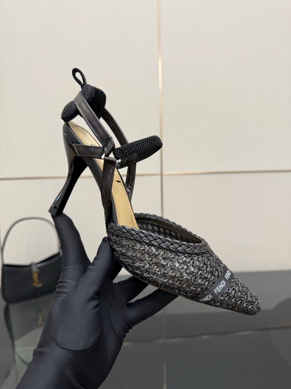 Fendi ladies heeled sandal shoes shown on hand, black textured upper and stiletto heel