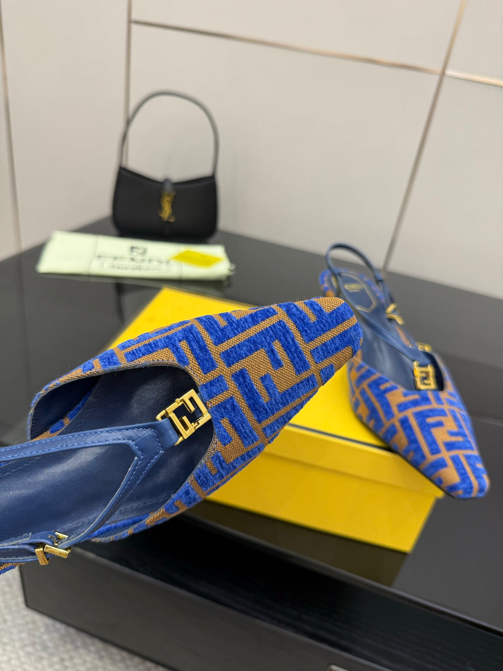 Close-up of blue Fendi logo-pattern slingback pumps with gold buckle strap