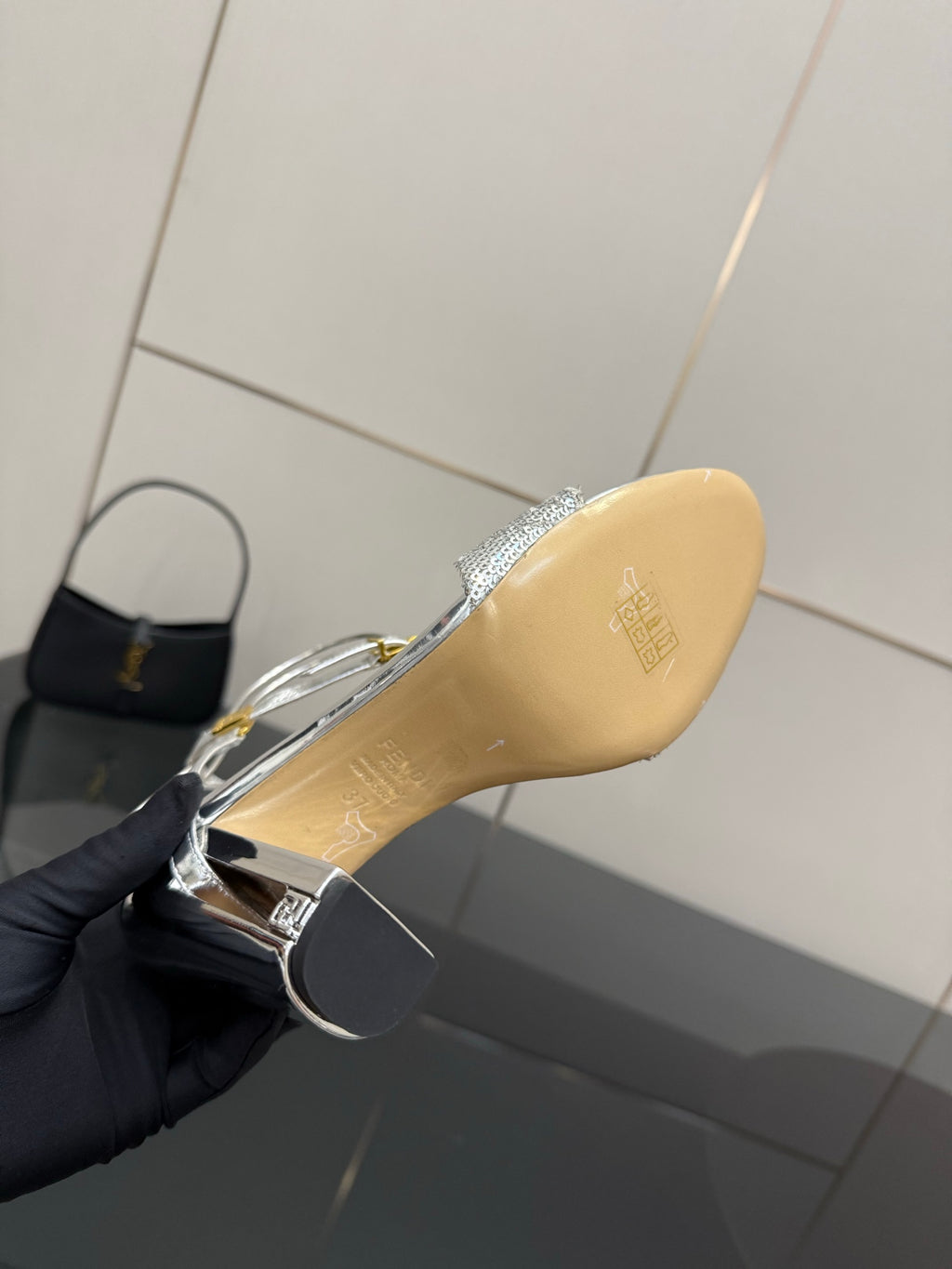 Fendi ladies silver sandal outsole close-up with gold logo and heel edge