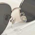 Round black-lens sunglasses with gold metal hinges and temple emblem