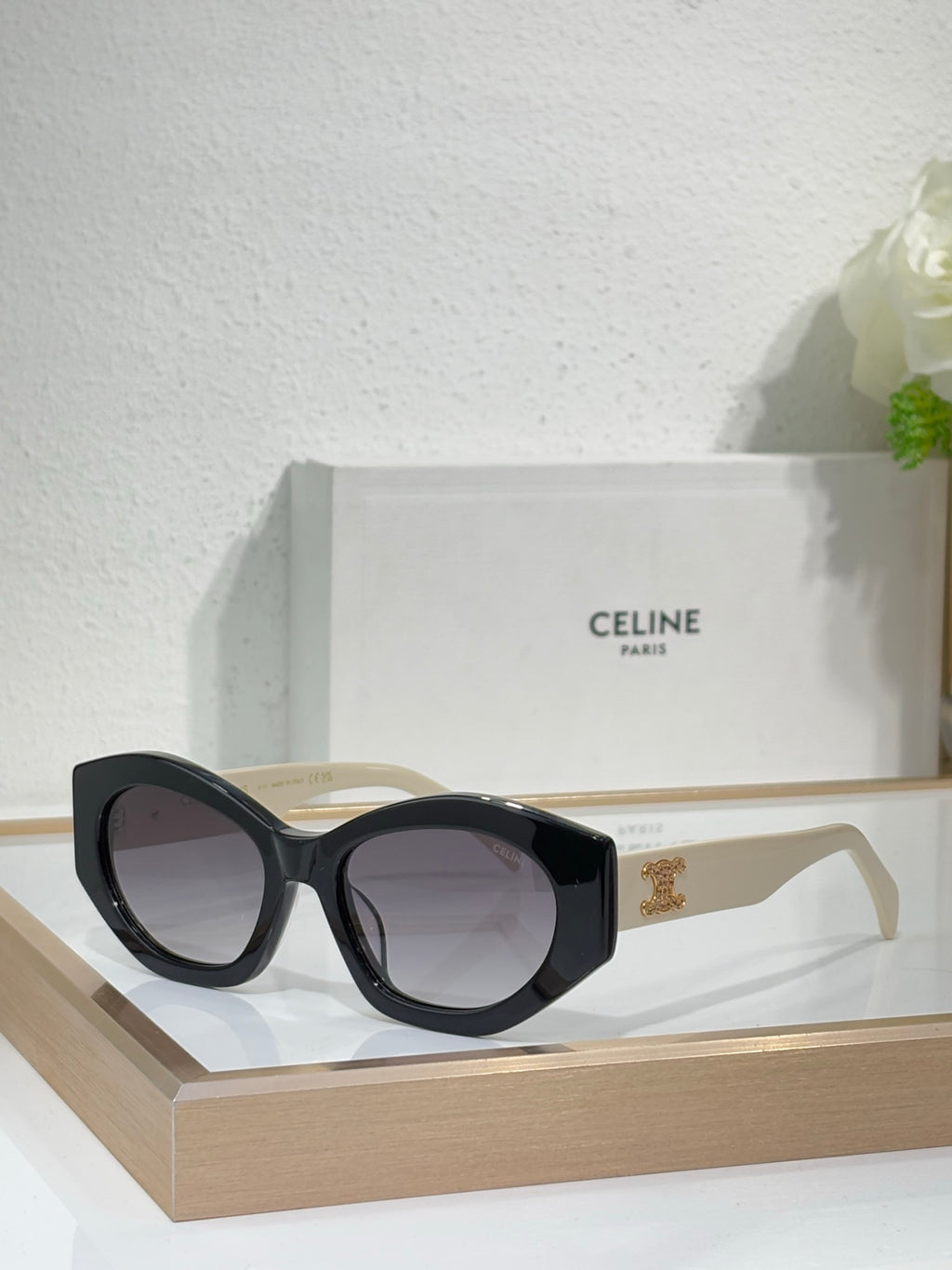 Celine sunglasses with black cat-eye frames, dark lenses, and gold emblem temple detail