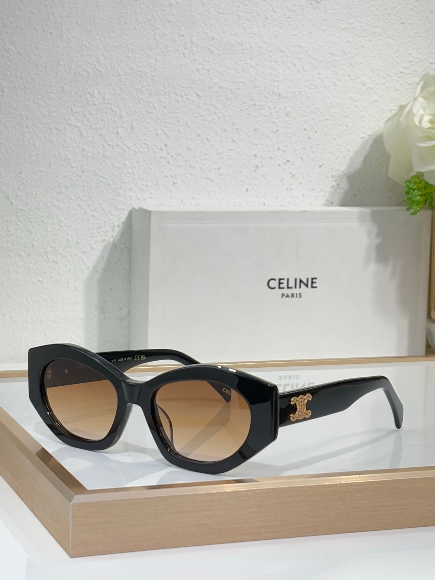 Celine sunglasses with black frames and warm tan lenses, featuring a gold temple logo