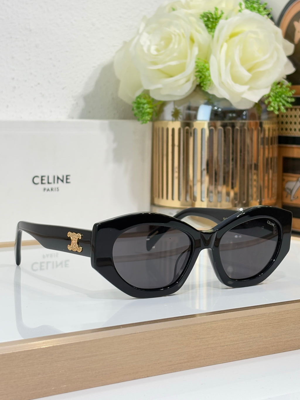 Celine sunglasses with black oversized frames, dark lenses, and gold temple emblem