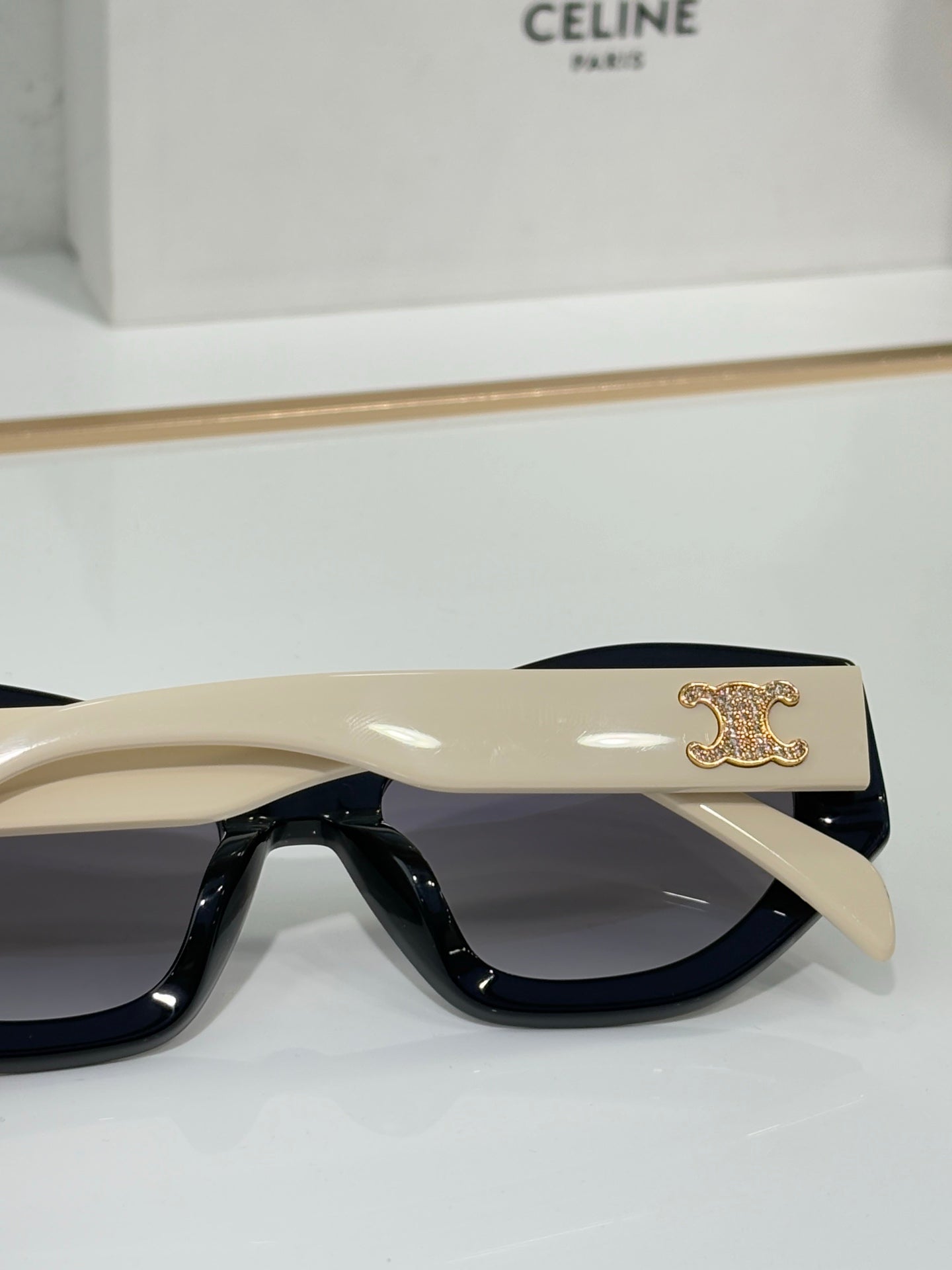 Celine sunglasses side view with beige temples, dark lenses, and gold crest logo