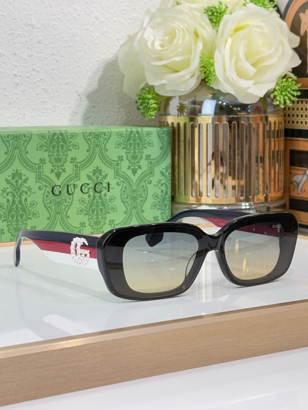 Gucci sunglasses with black frames and tinted lenses, cat-eye shape on display