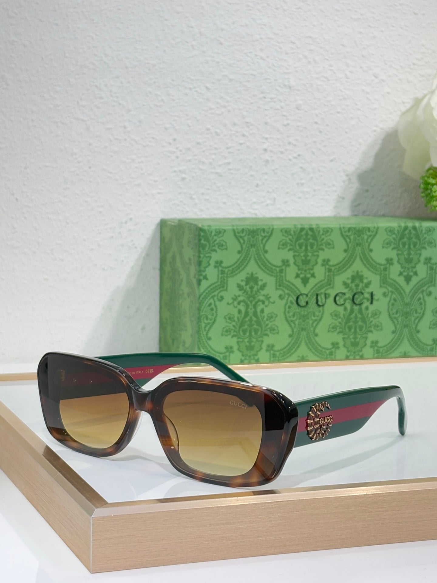 Gucci sunglasses with dark brown frames and golden lenses, cat-eye silhouette