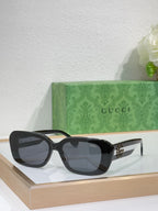 Gucci sunglasses with black frames and dark lenses, wide cat-eye shape