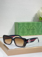 Gucci sunglasses with black frames and amber lenses, wide cat-eye design
