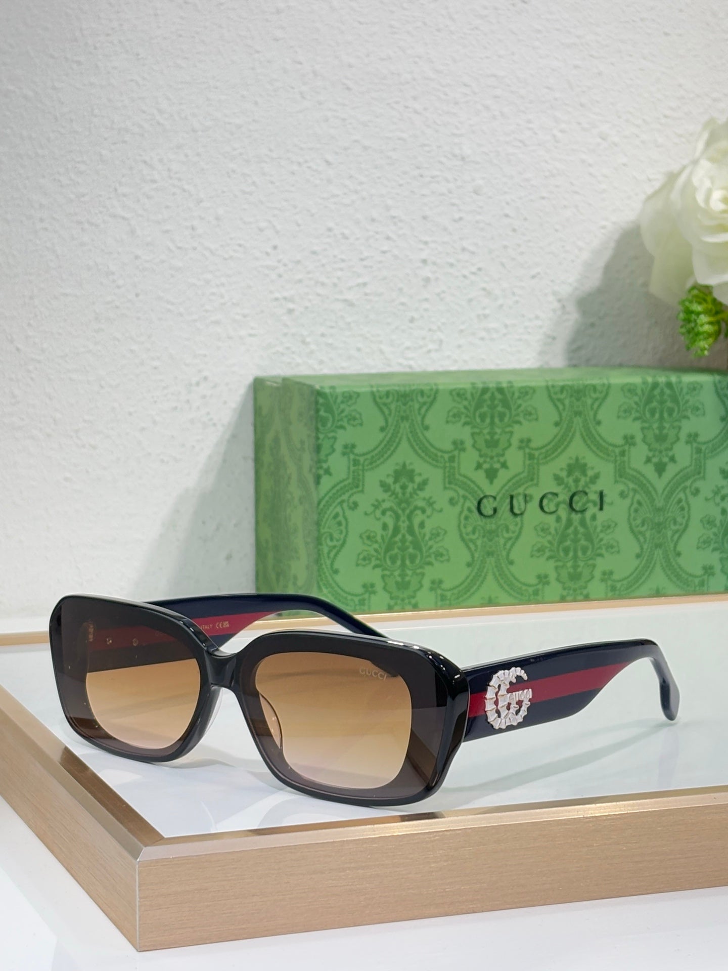 Gucci sunglasses with black frames and amber lenses, wide cat-eye design
