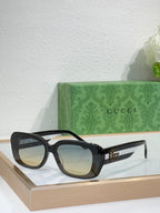 Gucci sunglasses with black frames and tinted blue lenses, cat-eye silhouette