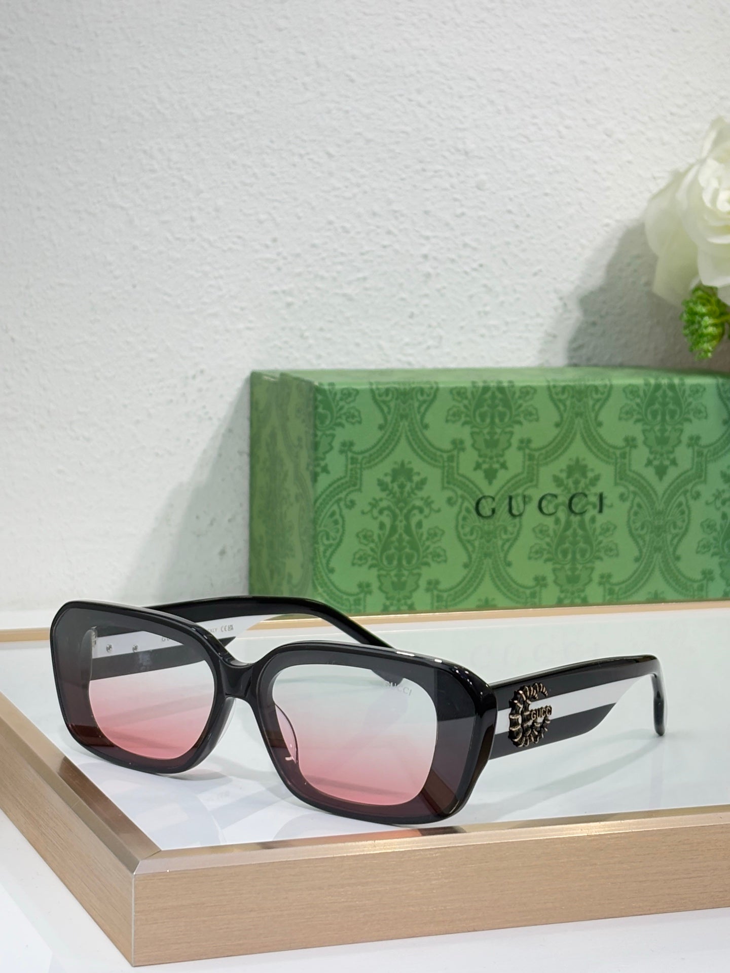 Gucci sunglasses with black frames and pink-tinted lenses, wide cat-eye style