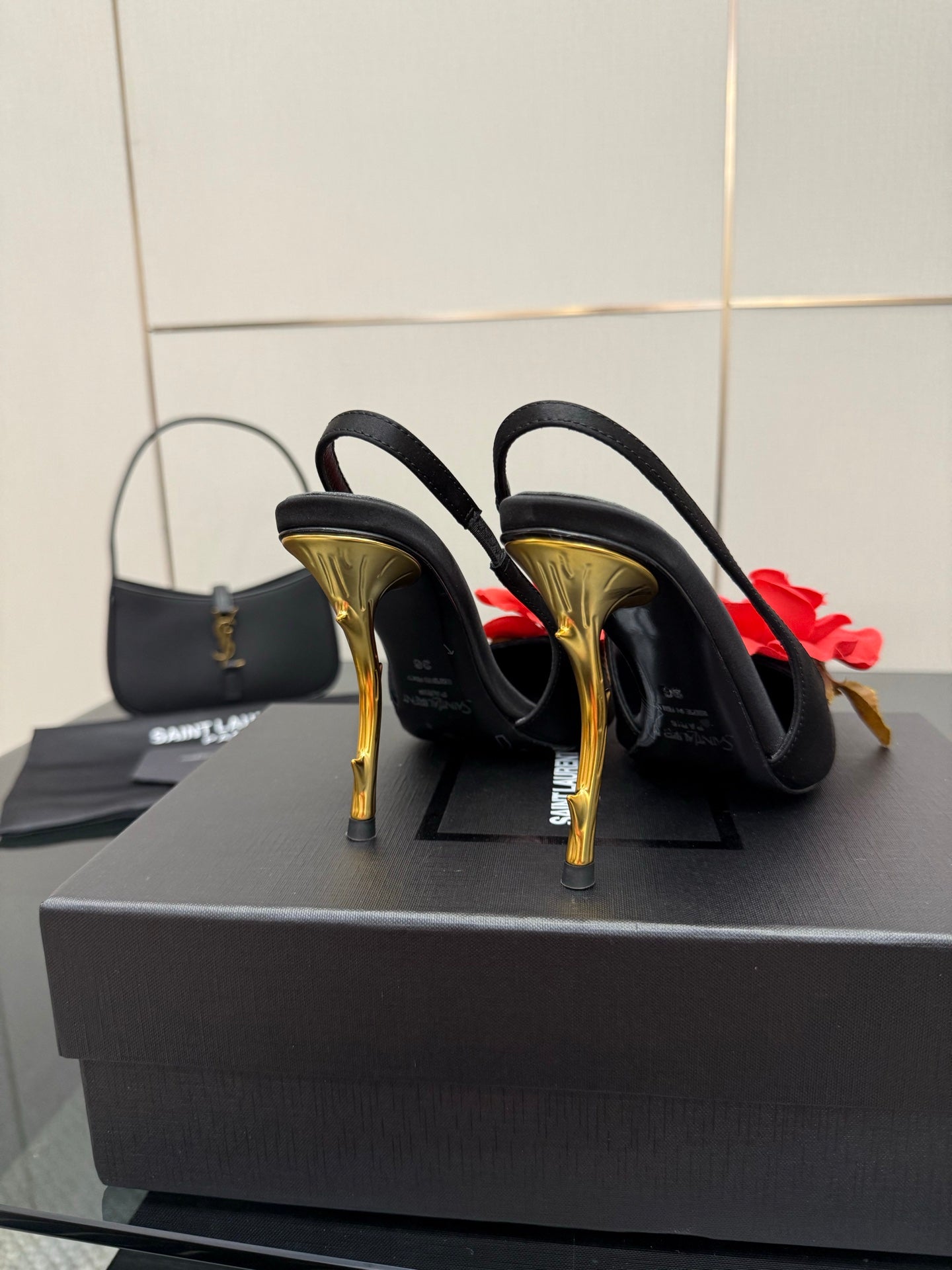 Back view of black slingback heels with red rose clips and gold stiletto heels