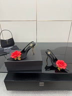 Black slingback heels with red rose clips and gold stiletto heels next to mini handbag