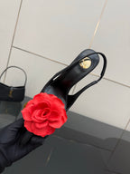 Black slingback heel held up, red rose clip and gold stiletto heel detail