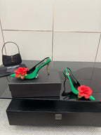 Green slingback pumps with red rose embellishments on the toe and gold-tone heels