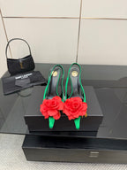 Green satin slingback heels with red flower embellishment and gold-tone stiletto heels