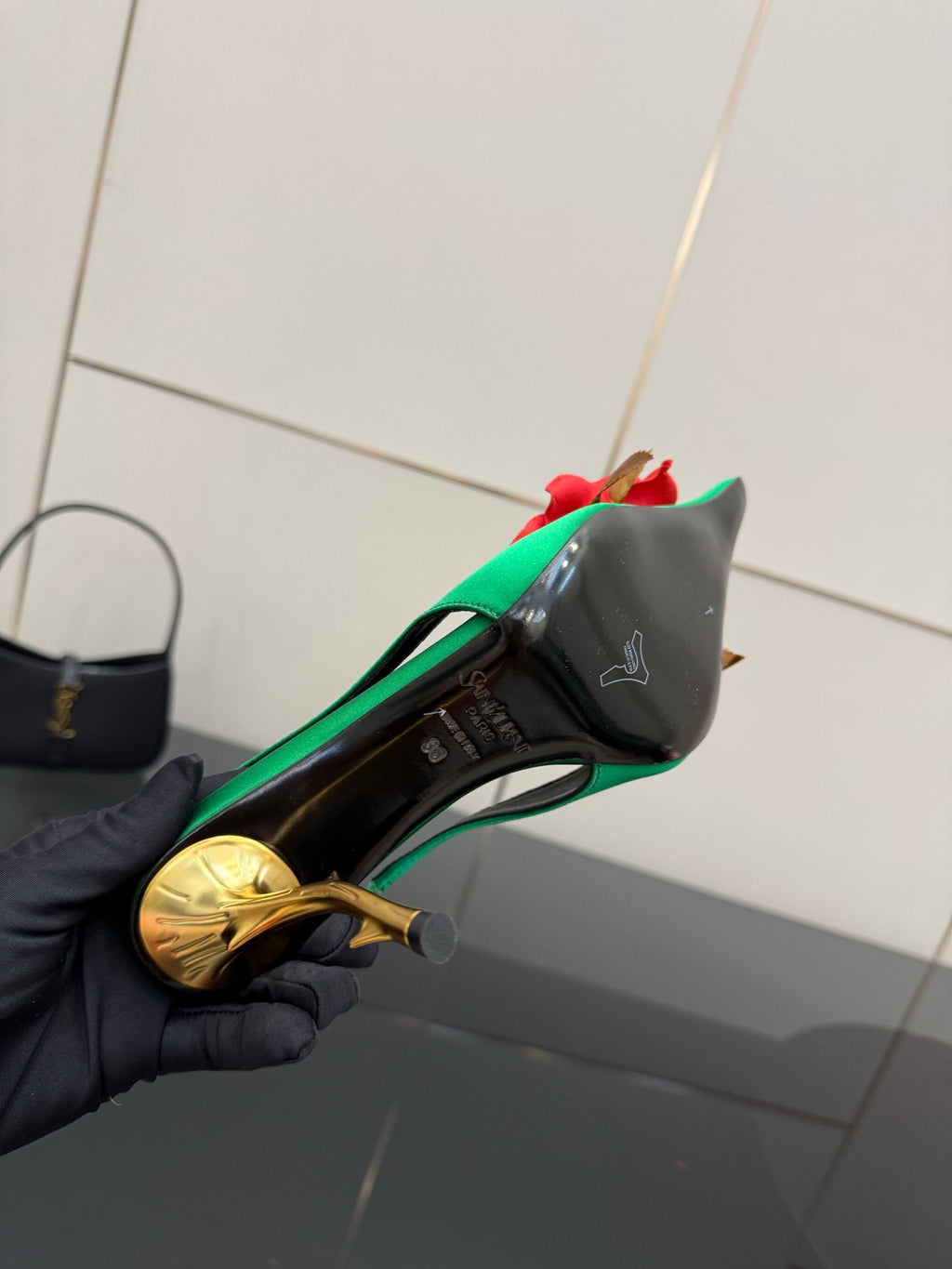 Green slingback heel showing insole detail; red flower accent and gold-tone heel