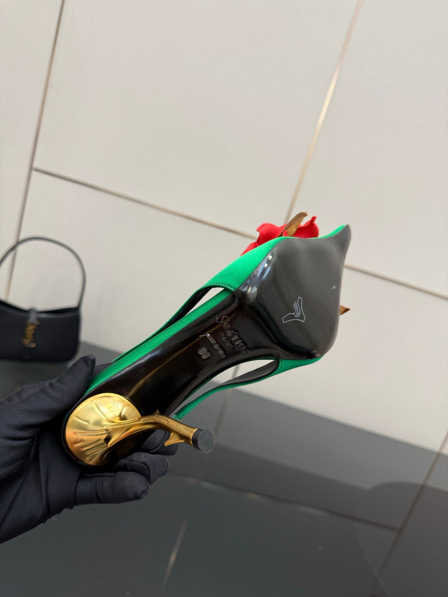 Green slingback heel showing insole detail; red flower accent and gold-tone heel