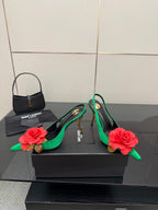 Green pointed-toe slingback heels with red rose embellishments and gold-tone heel tips