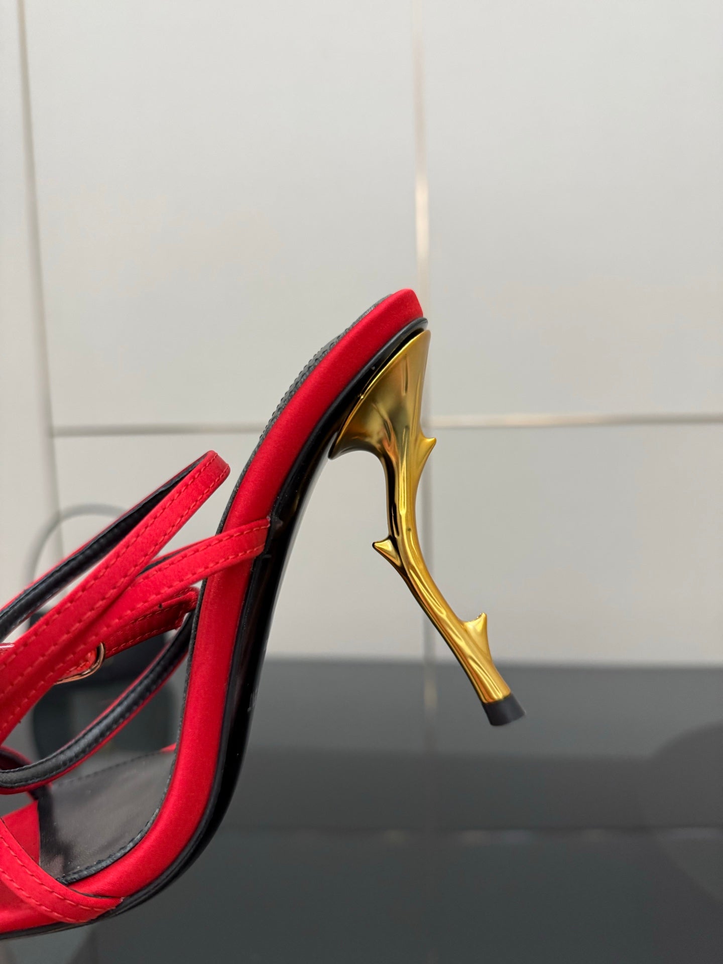 YSL ladies red sandal showing gold stiletto heel and black trim around the open toe