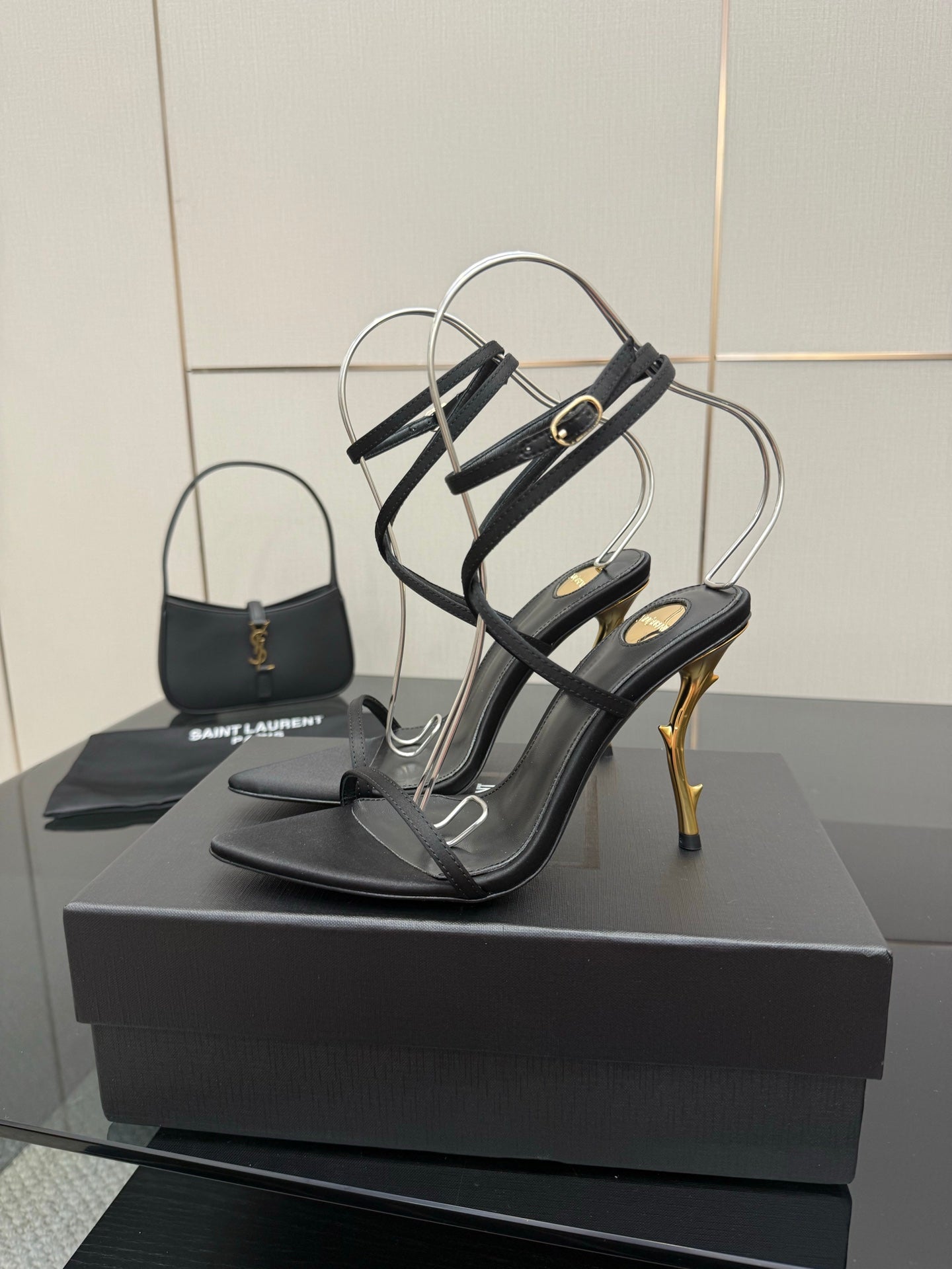 Black strappy high-heel sandals with thin ankle straps and gold-tone stiletto heels.