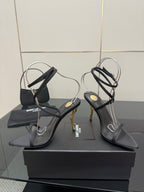 Pair of black strappy high-heel sandals with thin ankle straps and gold-tone heels.