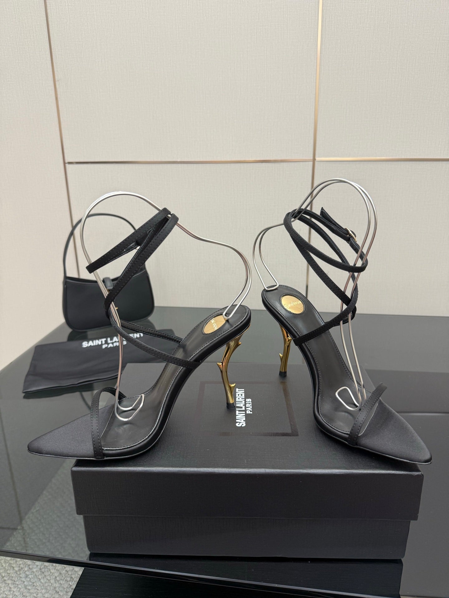 Pair of black strappy high-heel sandals with thin ankle straps and gold-tone heels.