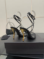 Black strappy sandals with ankle straps and gold-tone stiletto heel, rear view.