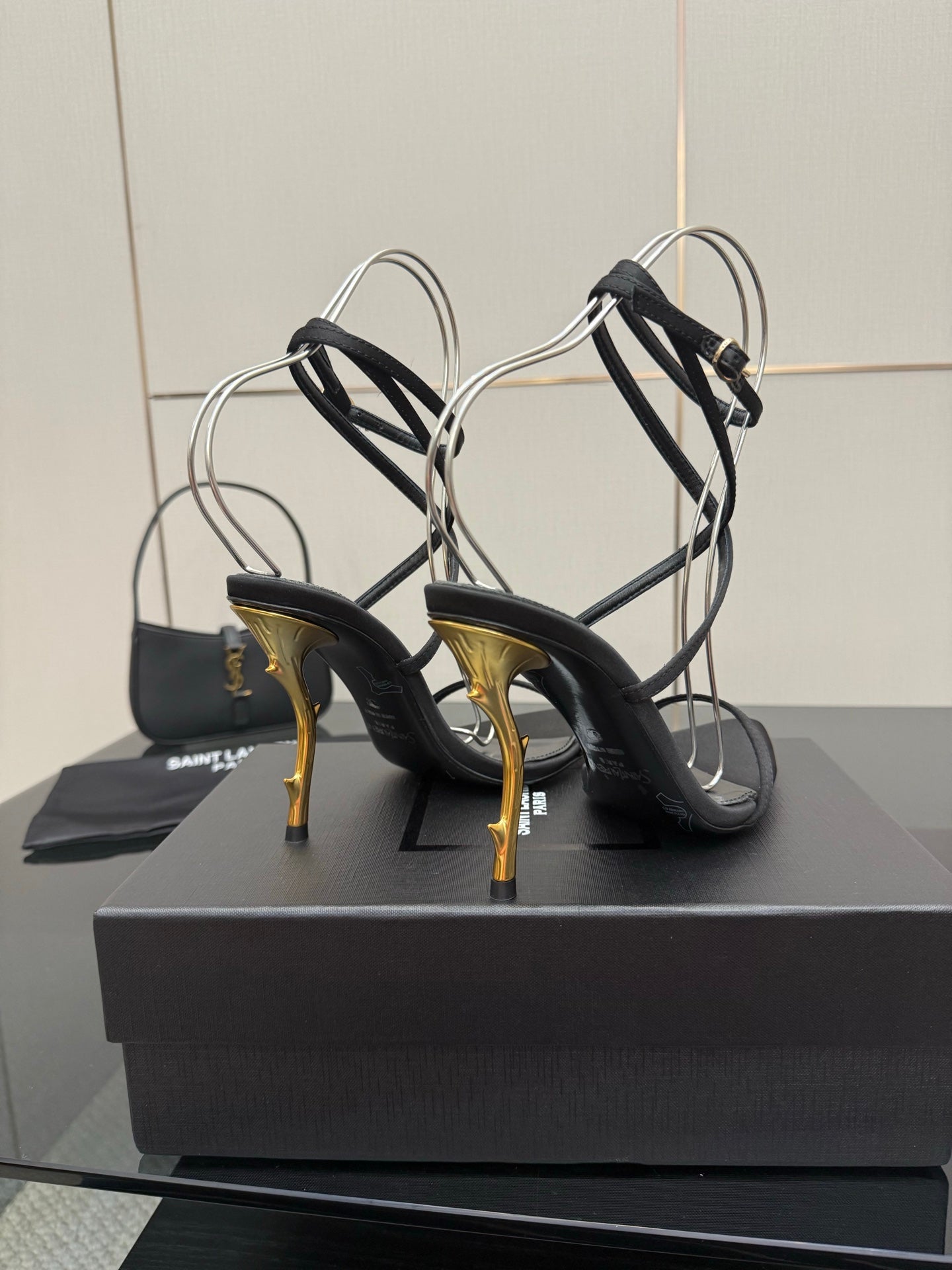 Black strappy sandals with ankle straps and gold-tone stiletto heel, rear view.