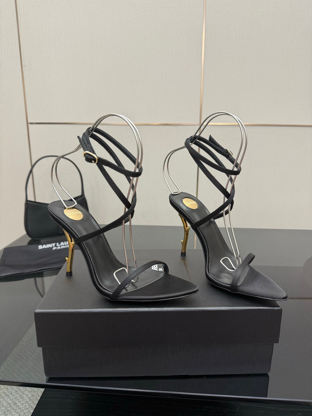 Black strappy high-heel sandal with thin ankle straps and gold-tone stiletto heel.