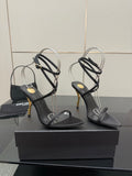 Black strappy high-heel sandal with thin ankle straps and gold-tone stiletto heel.