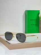 Round sunglasses with gold frame and dark gray lenses.
