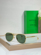 Round sunglasses with gold frame and dark green tinted lenses.