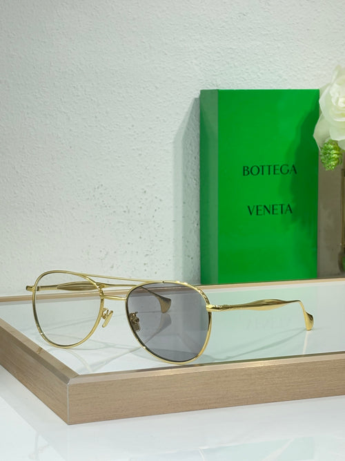 Round sunglasses with gold frame and dark gray lenses.