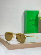 Round sunglasses with gold frame and amber tinted lenses.