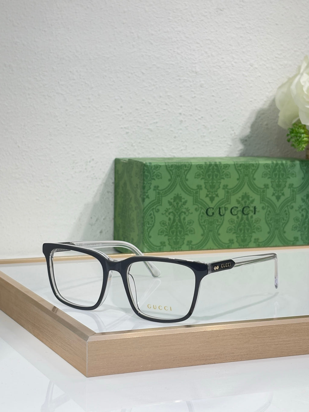 Gucci eyeglasses with dark rectangular frame and clear lenses on a shelf