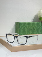 Gucci eyeglasses with dark rectangular frame and clear lenses on a shelf