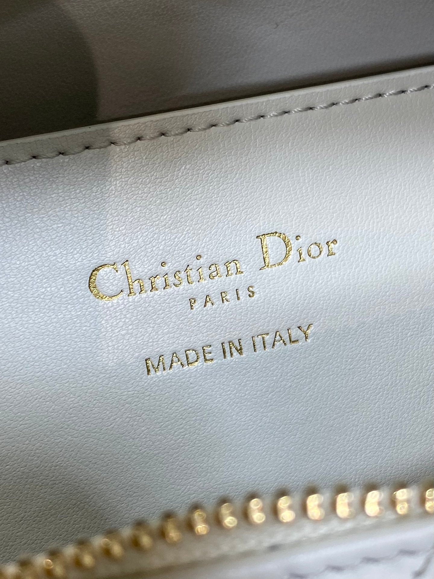 White leather bag label reading “Christian Dior Paris” and “Made in Italy”